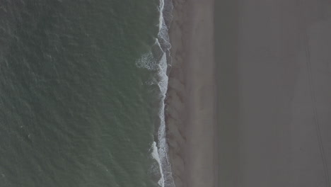 Generic-Brown-Beach-Pattern-and-Dark-Green-Ocean-on-Cloudy-Day,-Top-Down-Overhead-Aerial-Birds-Eye-View