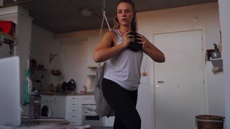 focused young sportswoman doing exercise with weight at home