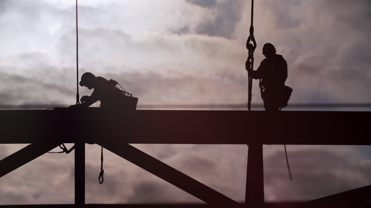 Silhouettes of Construction Workers on a Steel Structure