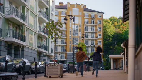 happy couple walking city modern residential area rear view. man making jump.