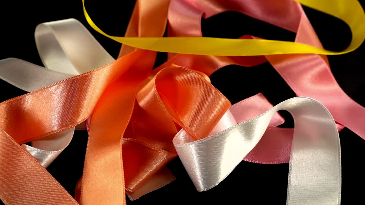 Satin ribbon on a black background. Slow motion