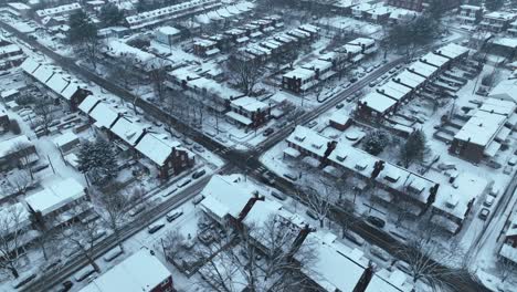 Aerial-drone-shot-of-a-snow-dusted-urban-neighborhood,-with-rows-of-houses-and-leafless-trees-under-a-cloudy-sky-in-the-USA