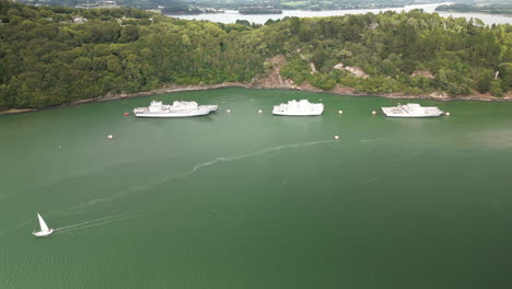 upward dolly aerial of group of boats floating on top of a large winding river