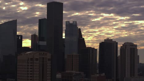 High-angle-Dolly-shot-moving-backwards-away-from-downtown-Houston,-Texas-during-sunset