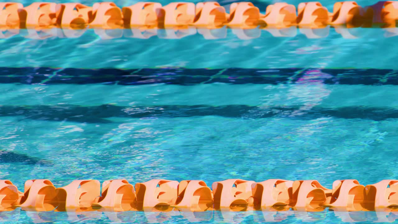 Bright sunlight illuminates blue pool water and orange lane dividers, creating dynamic ripples and reflections. Overhead camera remains steady, emphasizing texture and color