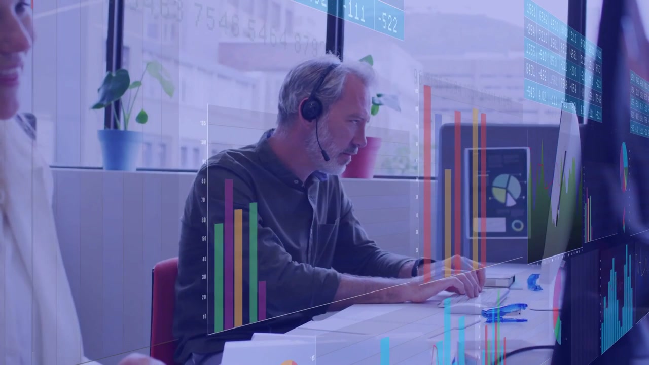 Mand med headset overvåger og skriver ved et operations-dashboard, modtager nye data og animerer diagrammer.