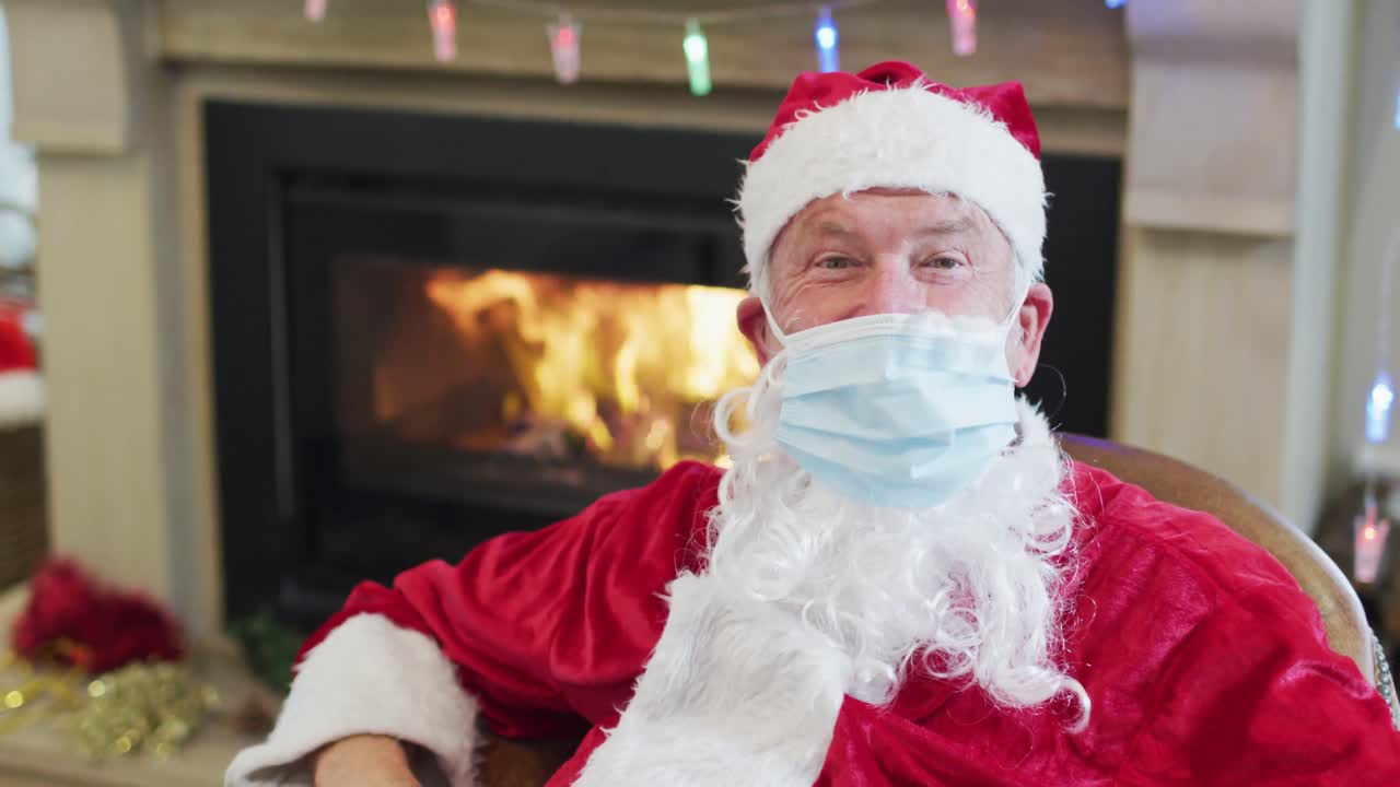 산타클로스가 집에서 의자에 앉아 얼굴 마스크를 쓰고 있다.