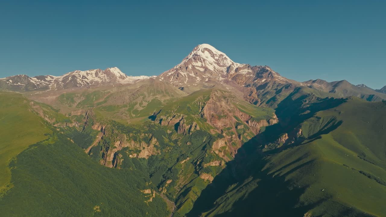 Majestic Kazbegi peaks under clear blue skies, exuding serenity and awe