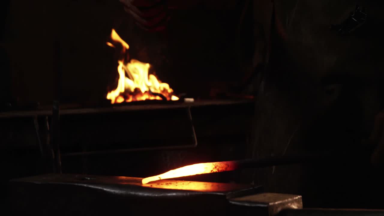 sección media de un herrero trabajando en una barra de hierro