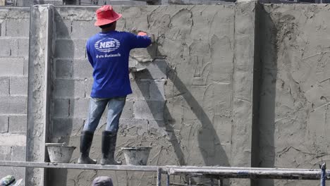 worker applying plaster to a brick wall steadily.