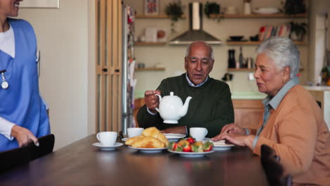 a nurse pours tea for an elderly couple in their home.