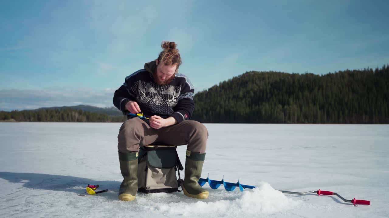 hombre preparando su caña de pescar - pesca en el hielo en un lago congelado en noruega