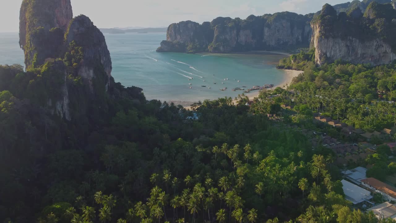 Beautiful aerial view of Railay Beach near Ao Nang, Thailand, showing limestone cliffs, turquoise sea, palm trees, and a laid-back tropical coastline only accessible by boat.