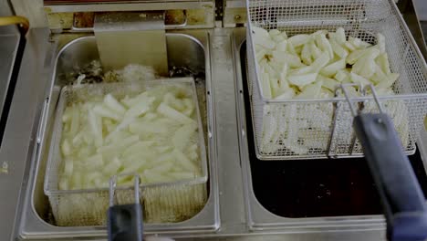 removing fried potato from boiled oil to hang on high stand and shaking other one