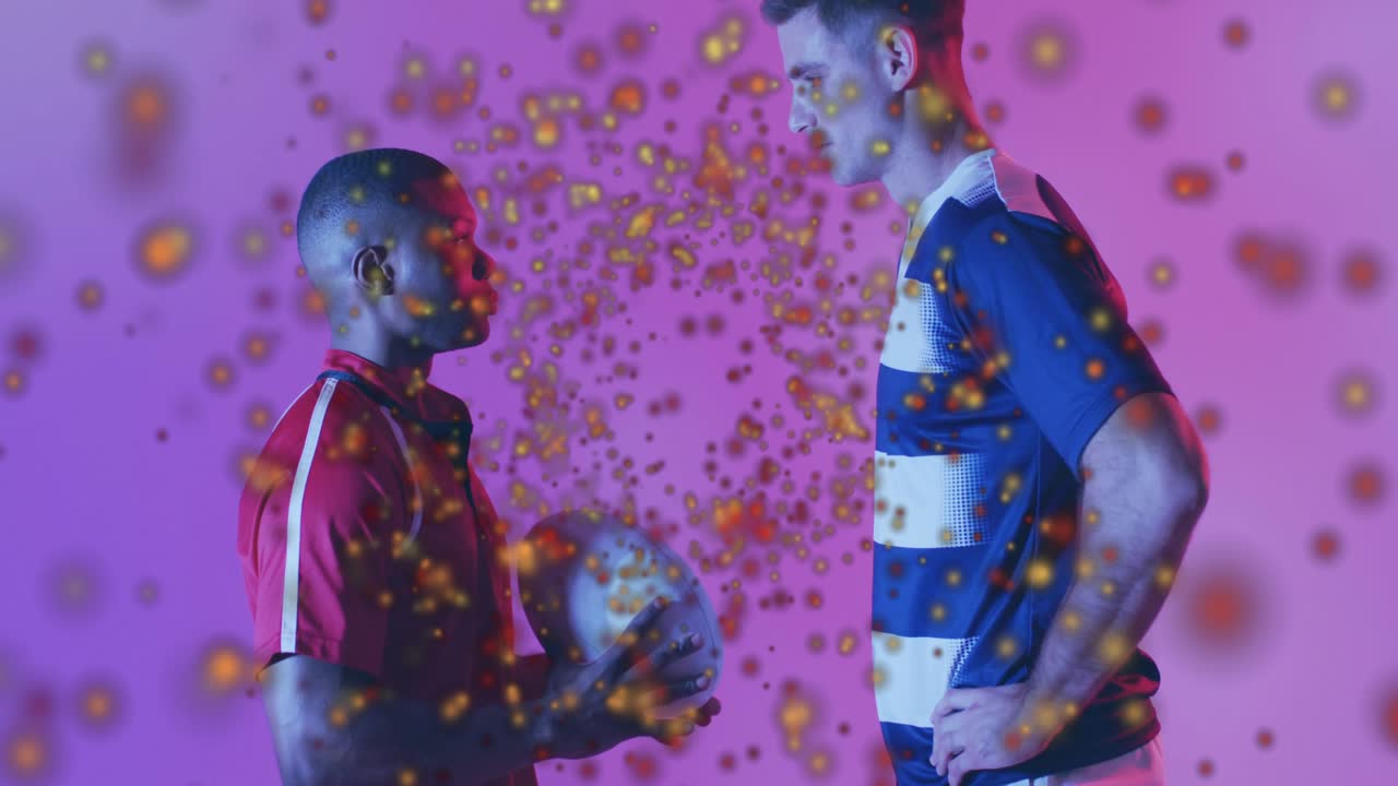 Two athletes raising rugby ball in sports demo on gradient emitting swirling golden particles