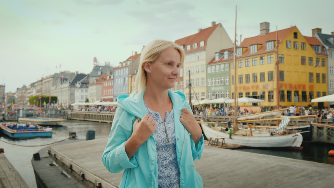 한 여성이 가장 인기 있는 유명한 다채로운 주택을 배경으로 운하를 따라 산책합니다.