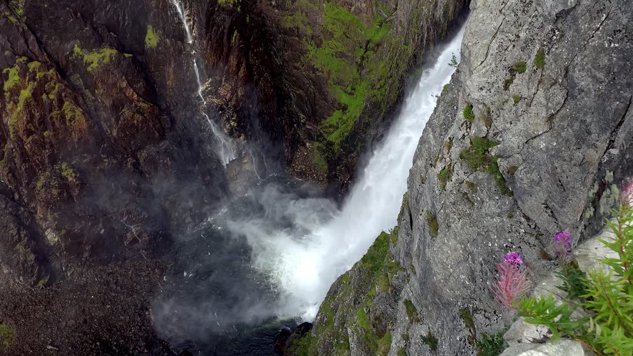 Vøringsfossen Waterfall in Hardangervidda National Park, Eidfjord, Norway, tumbling down rocky cliff into pond below. Slow motion, static high angle view