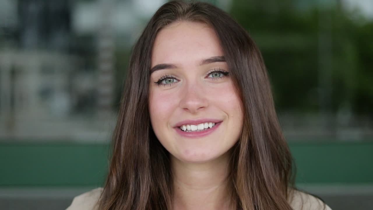 chica caucásica mirando a la cámara, sonriendo, corrigiendo el cabello