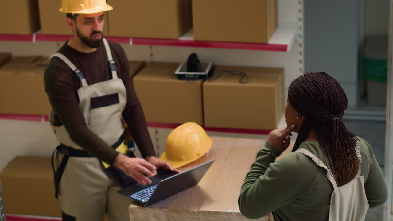Warehouse workers discussing inventory with laptop