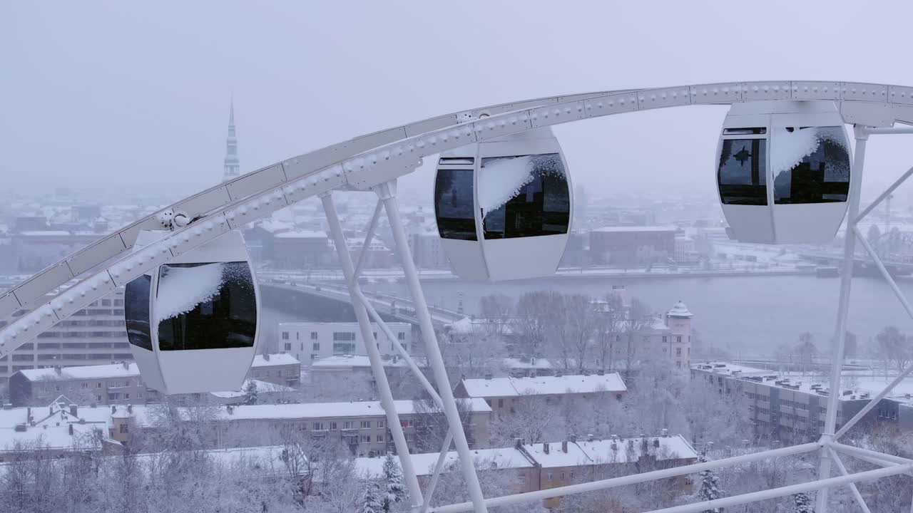 Aerial winter view of snowy Ferris wheel cabins and urban Riga city background