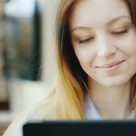 a young caucasian woman rests in a cafe uses a tablet