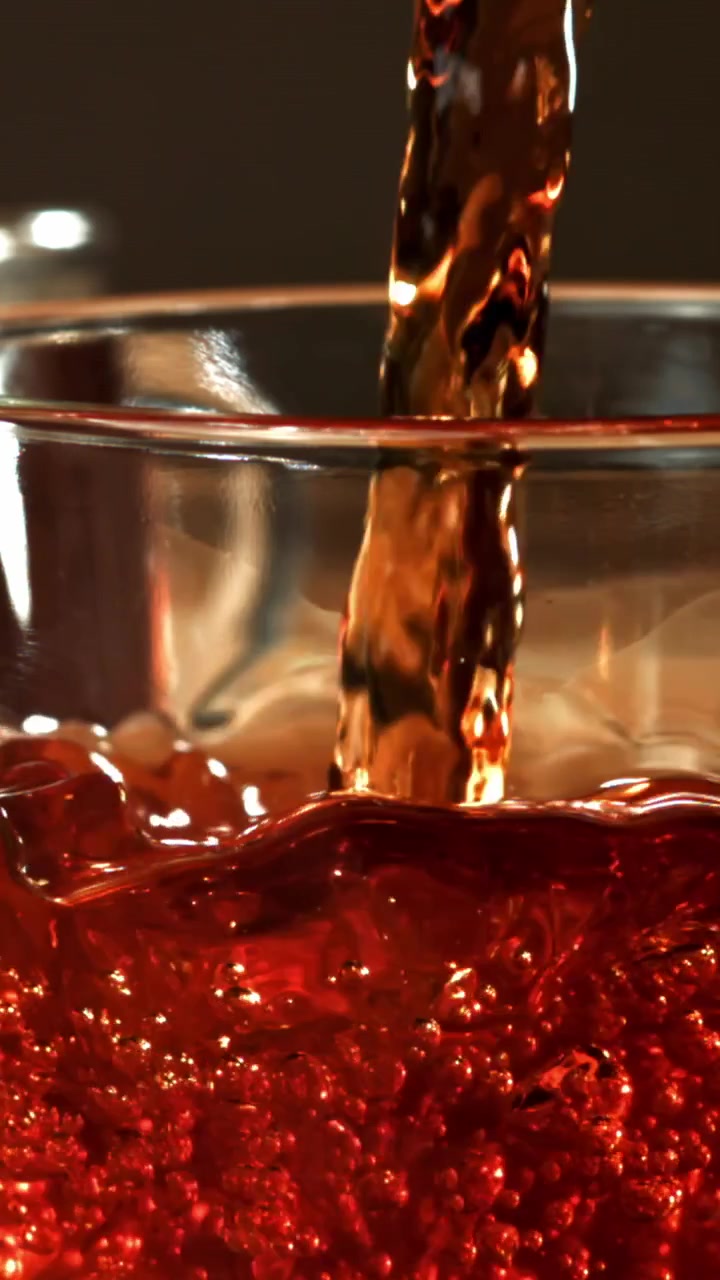 Bevanda Rossa Rinfrescante che si Versa in un Bicchiere Trasparente