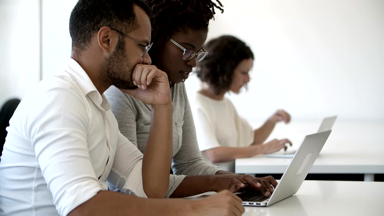 empleados enfocados usando computadora portátil mientras están sentados en la oficina