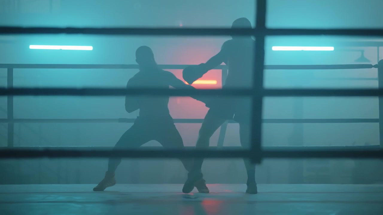 Sagome di pugili che fanno sparring in un ring illuminato al neon