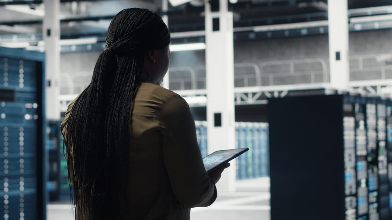 Woman walking through data center server rows, checking equipment