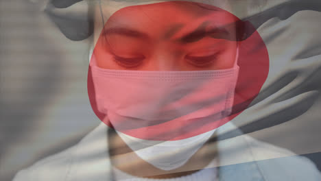 Animation-of-flag-of-japan-waving-over-woman-wearing-face-mask-during-covid-19-pandemic