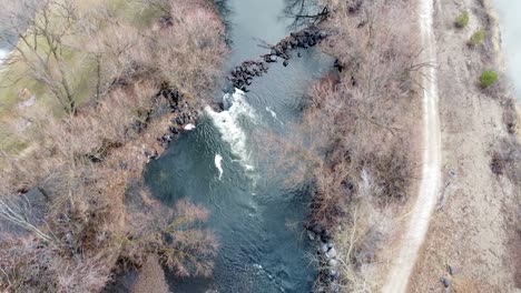 small river dam and rapids on scenic, idyllic, willow tree lined river in winter in rural countryside in boise, idaho, usa