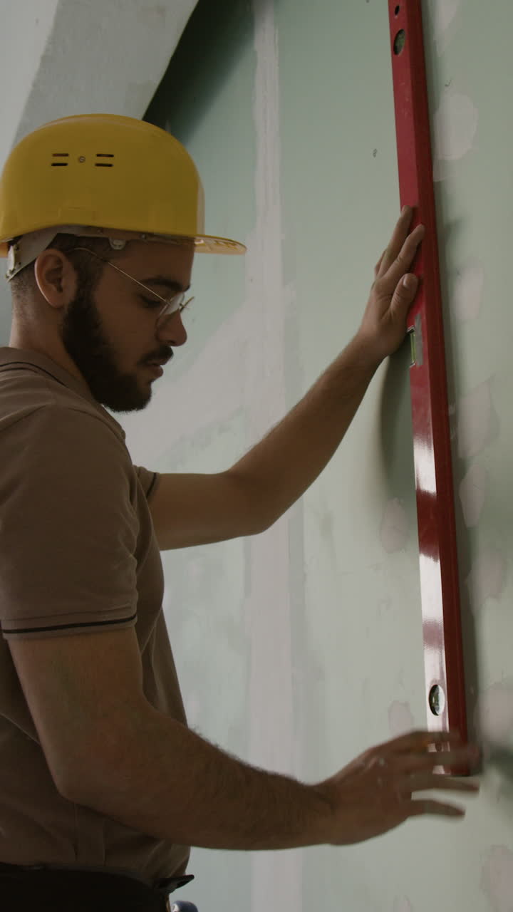 Construction worker using level on wall