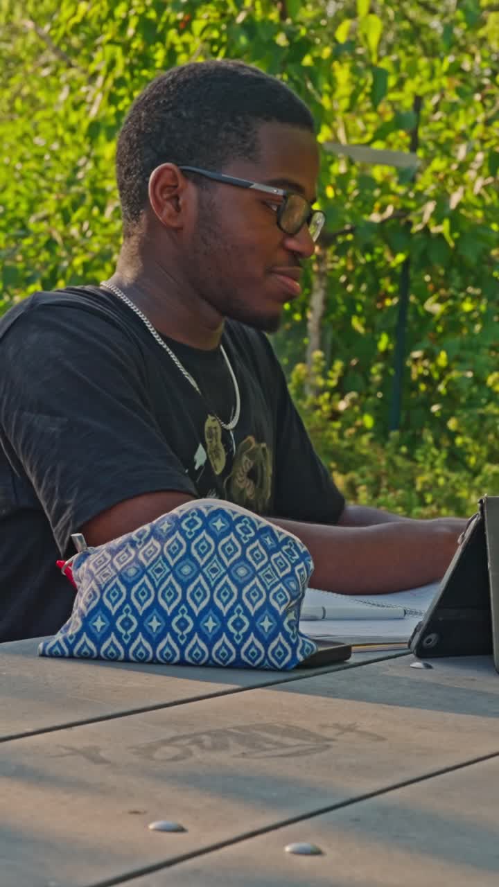 Afroamerikansk mann som gjennomgår notater fra undervisningen i en park utendørs.