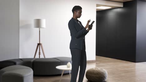 businesswoman in suit messaging on mobile phone in modern open plan office