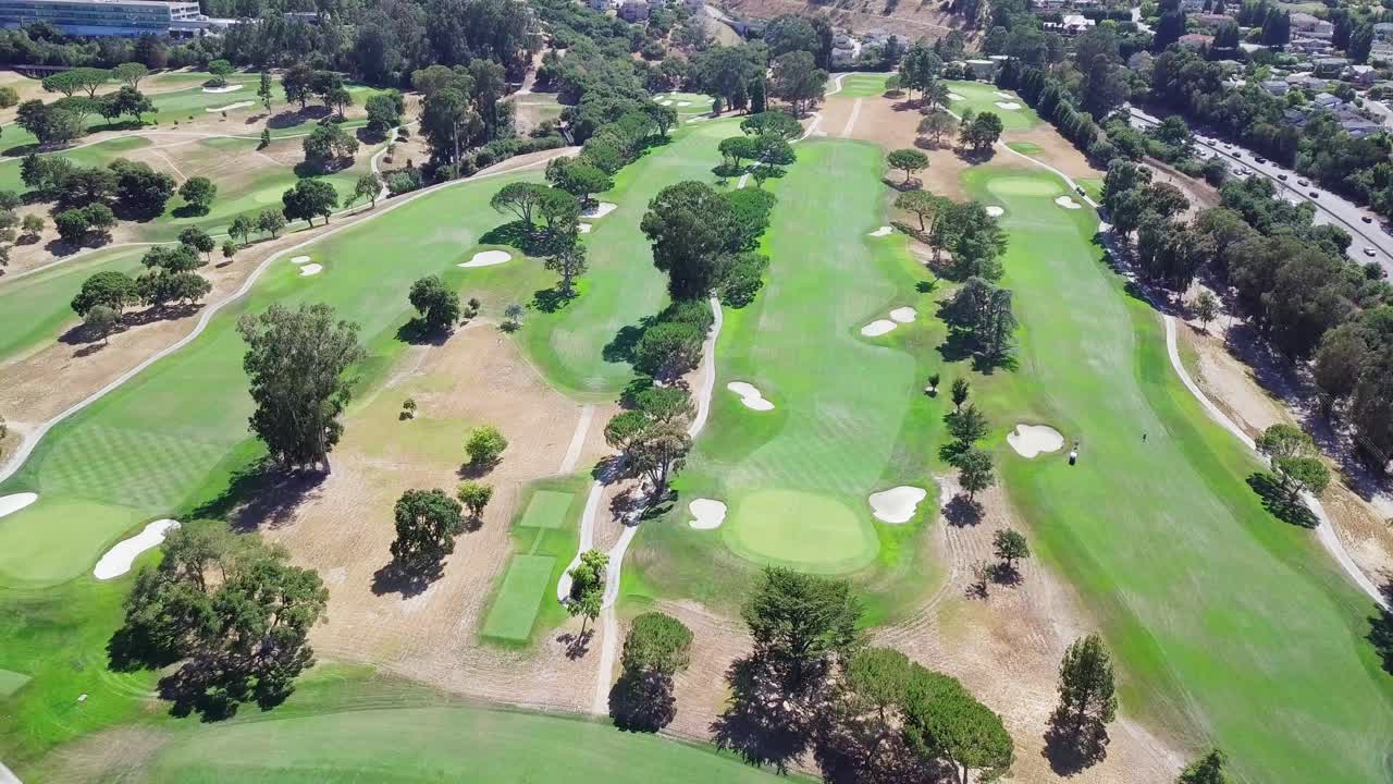 화창한 날 배경에 산이 있는 골프 코스 필드의 공중 헬리콥터 샷이 왼쪽으로 회전합니다.