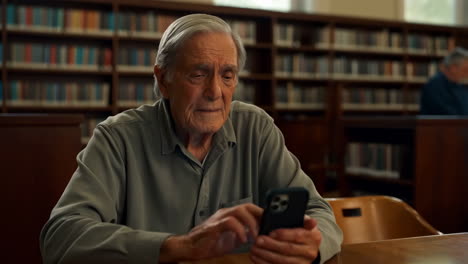 elderly man using smartphone in library