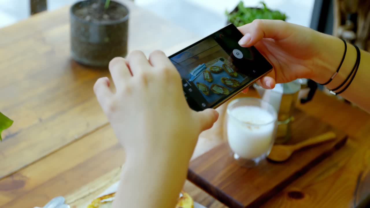mujer fotografiando la bandeja de bocadillos con teléfono móvil 4k