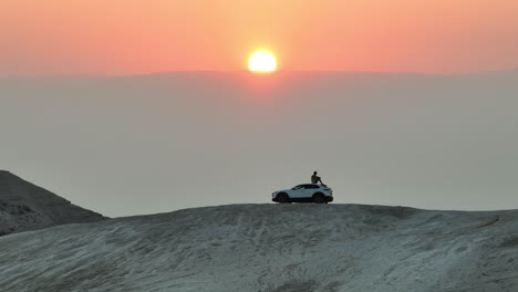 El-Hombre-Se-Sienta-En-Una-Colina-Del-Desierto-Con-Vistas-Al-Amanecer-En-La-Parte-Superior-De-Un-Camión-Mazda