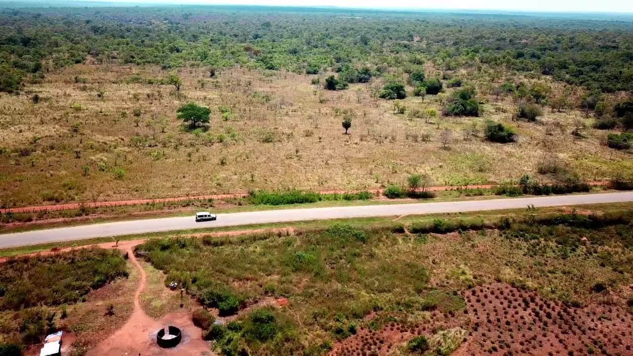 Tourist Vehicles On Safari Driving On Rural Road In Kenya, East Africa. - Drone Tracking Shot