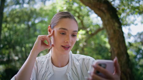 woman speaking smartphone camera sitting green park closeup. girl video call