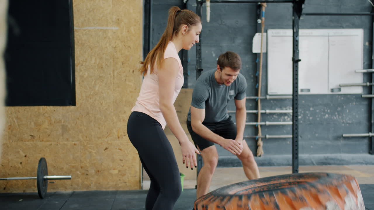 Couple working out with tire flip in gym