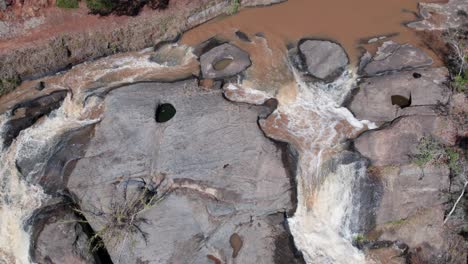 Vista-Aérea-De-Arriba-Hacia-Abajo-De-Los-Flujos-De-Agua-Sobre-Las-Rocas-En-El-Bosque