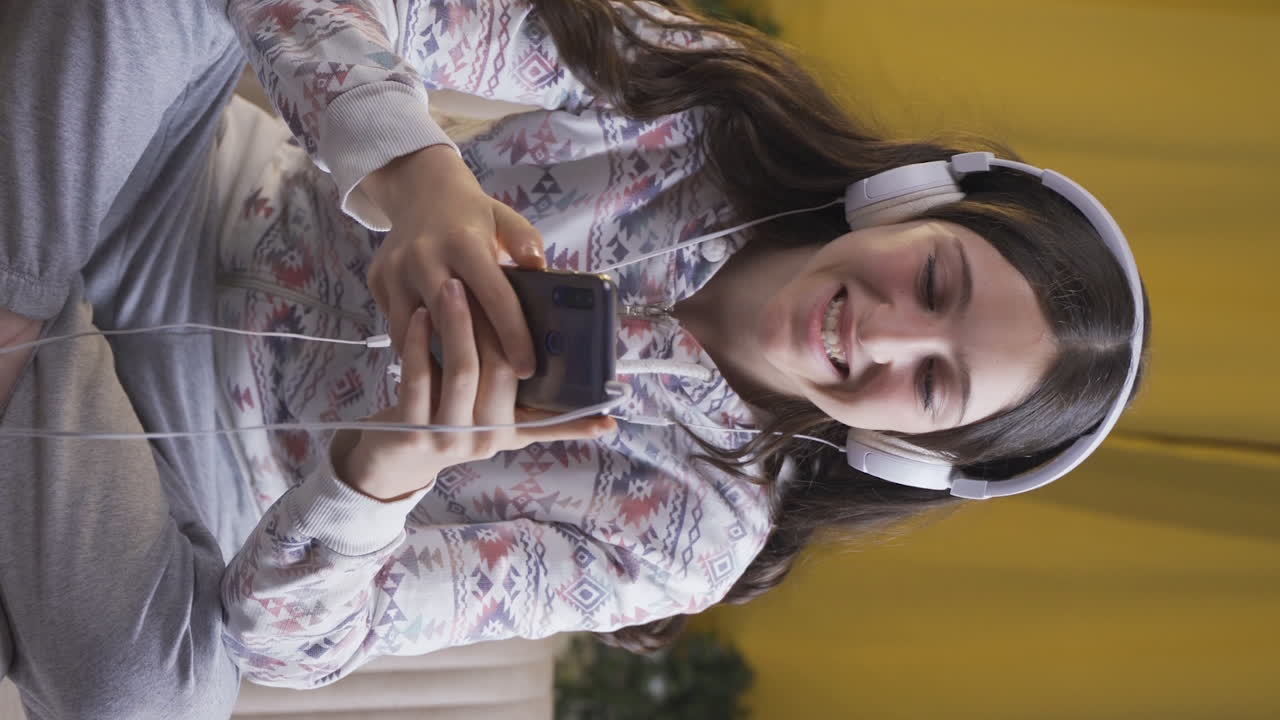video vertical de una mujer joven usando las redes sociales en el teléfono riendo por la noche en casa.