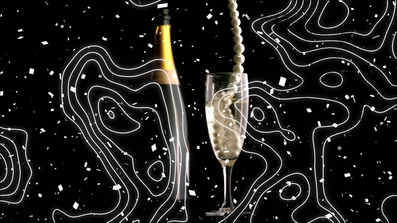 Topography and confetti falling over pearl beads falling in champagne glass against black background