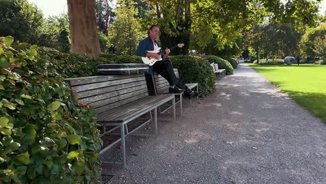 a man plays the white guitar in the park