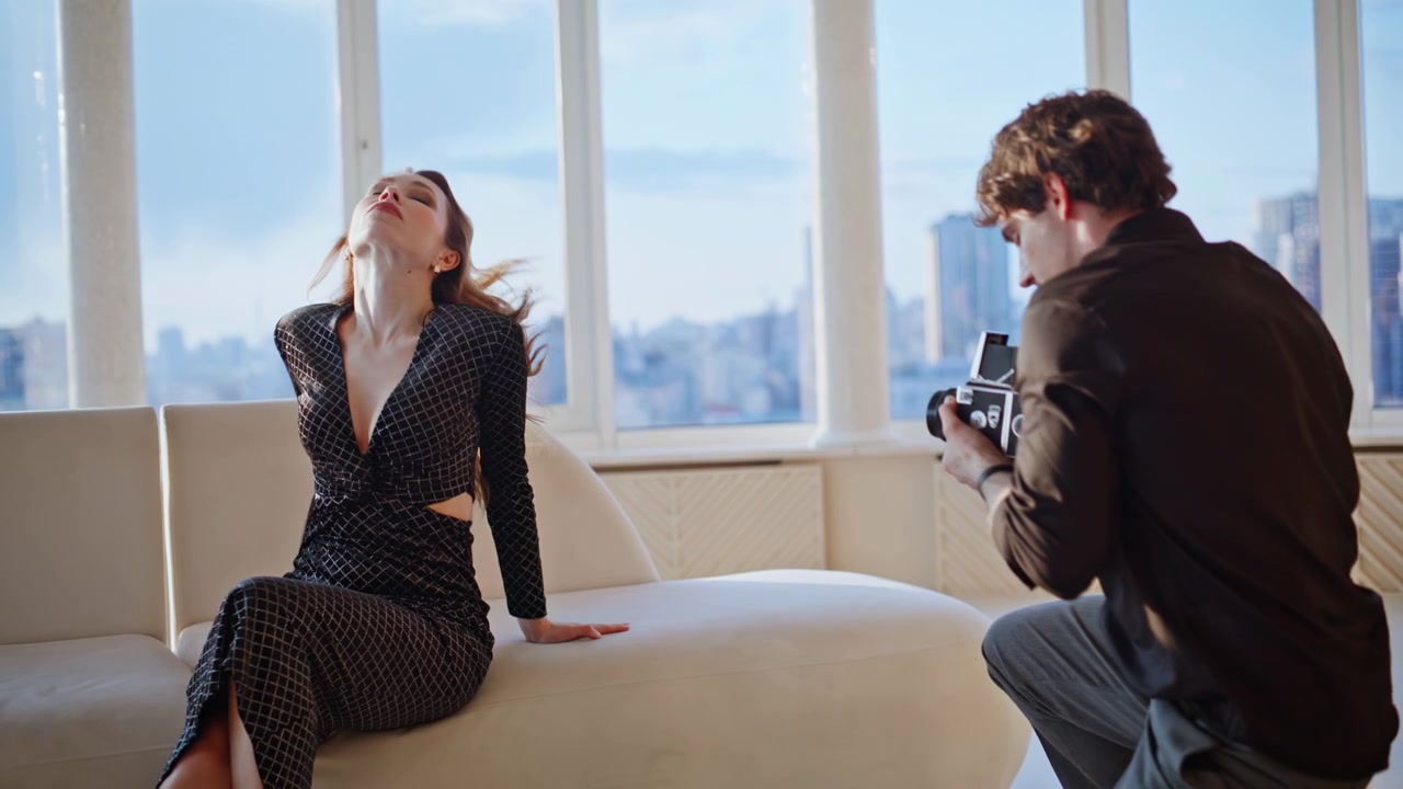 Fotografo che scatta a modella glamour in studio. Uomo che dirige la posa della donna in appartamento di lusso