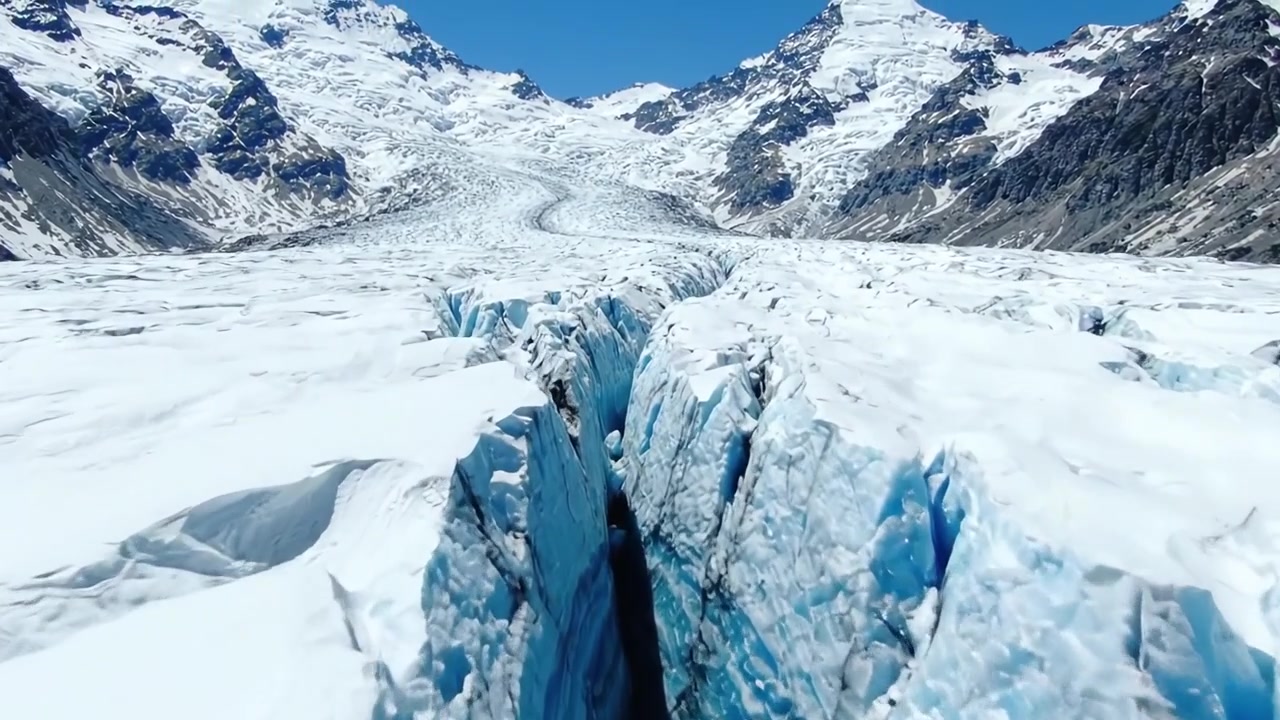 Majestic Glacial Landscape Featuring Impressive Cracks and Ice Formations Underneath Bright Blue Sky in a Remote Mountainous Region