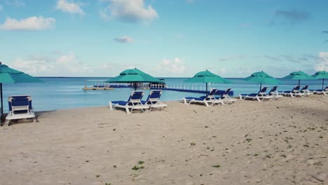 orbit drone shot of chairs and umbrellas on white sand beach