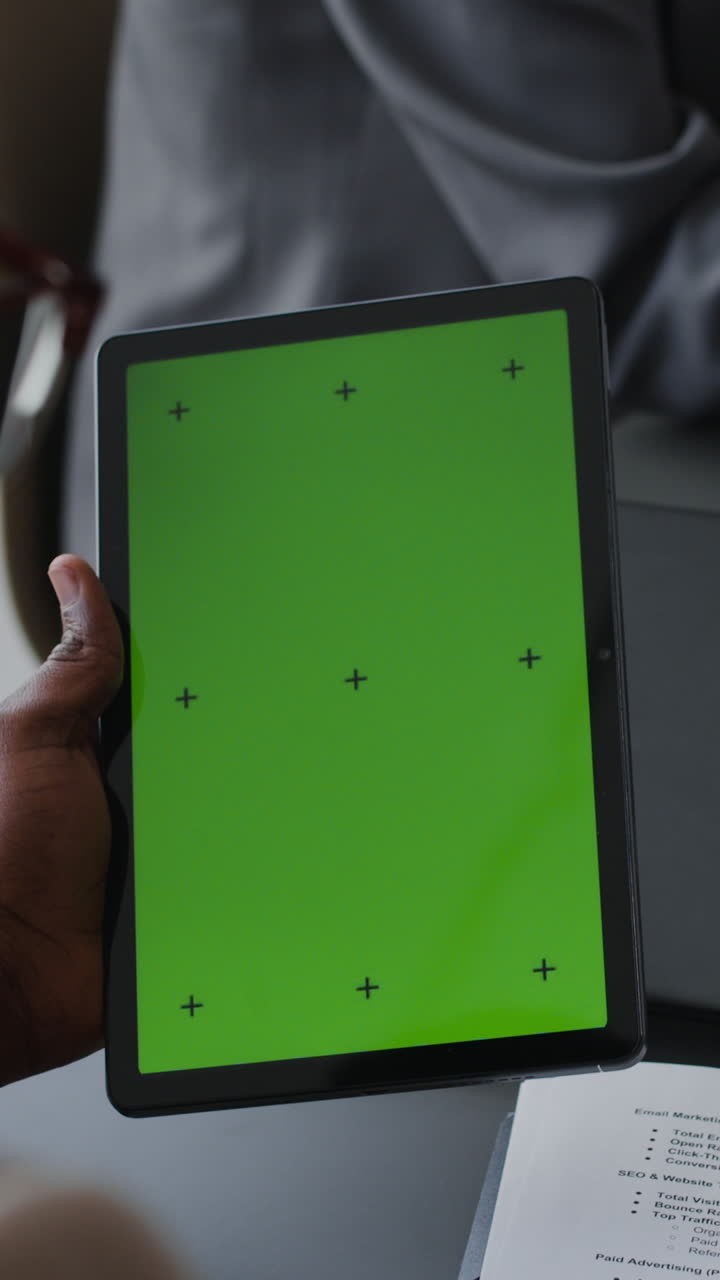 persona que sostiene una tableta con una pantalla verde