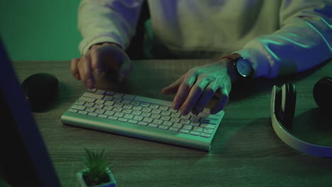 Male-hands-typing-on-the-keyboard-working-with-a-computer-on-a-colorful-background.-Close-up.